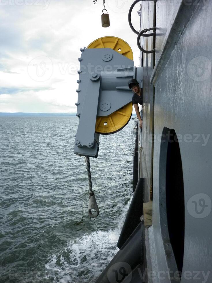 A large mooring line with rollers at the stern of the ship. A man next to the rollers of a barge mooring line. photo