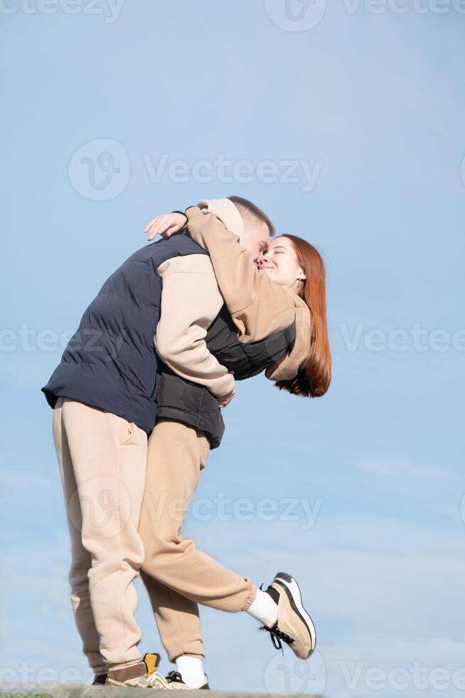 cheerful romantic couple dating and hugging outdoors, sky background photo