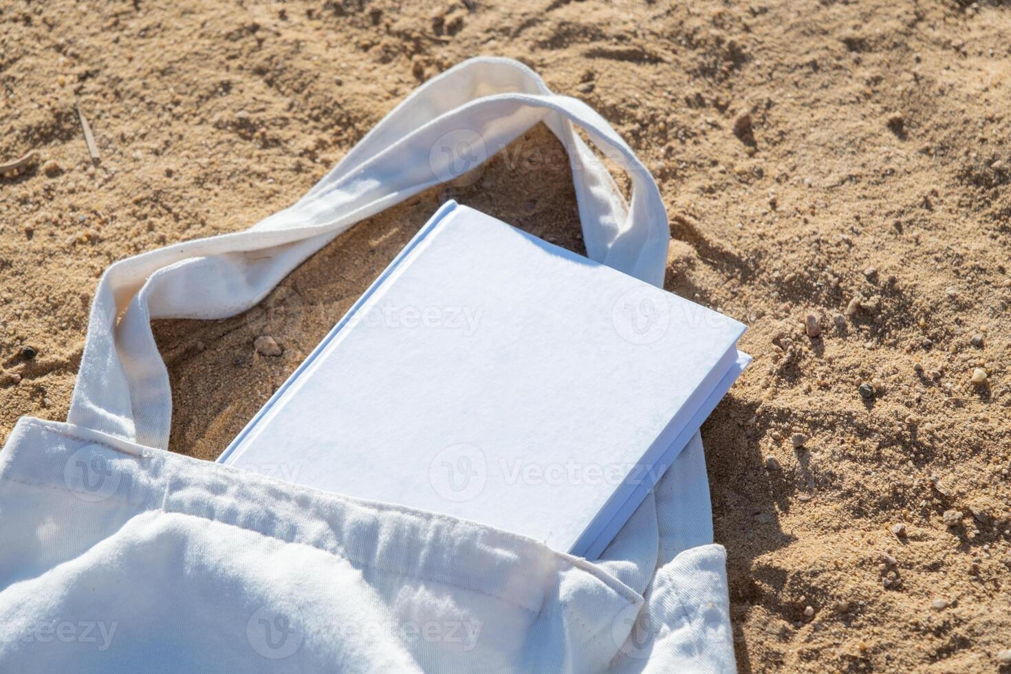 Mockup shopper handbag and book, beach sand background photo
