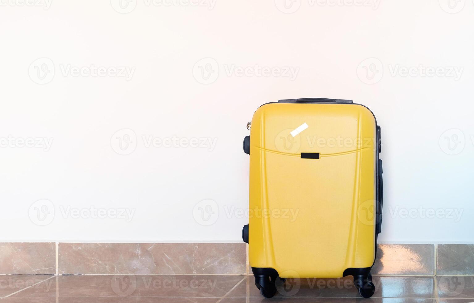 yellow suitcase on white wall background in hotel room photo