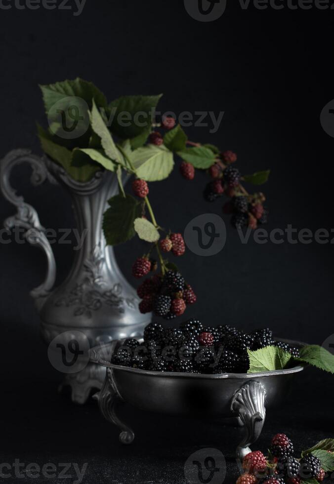 un lleno plato de el maduro moras, una puntilla de rojo bayas en un estaño cuenco foto