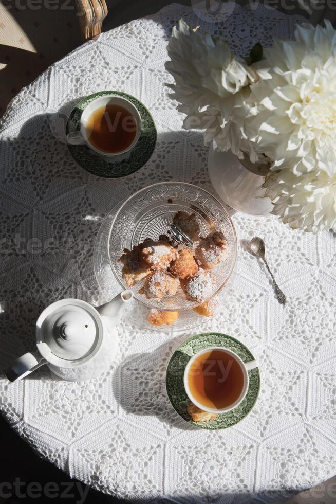 English style tea break, still life with flowers and donuts in the morning sun photo