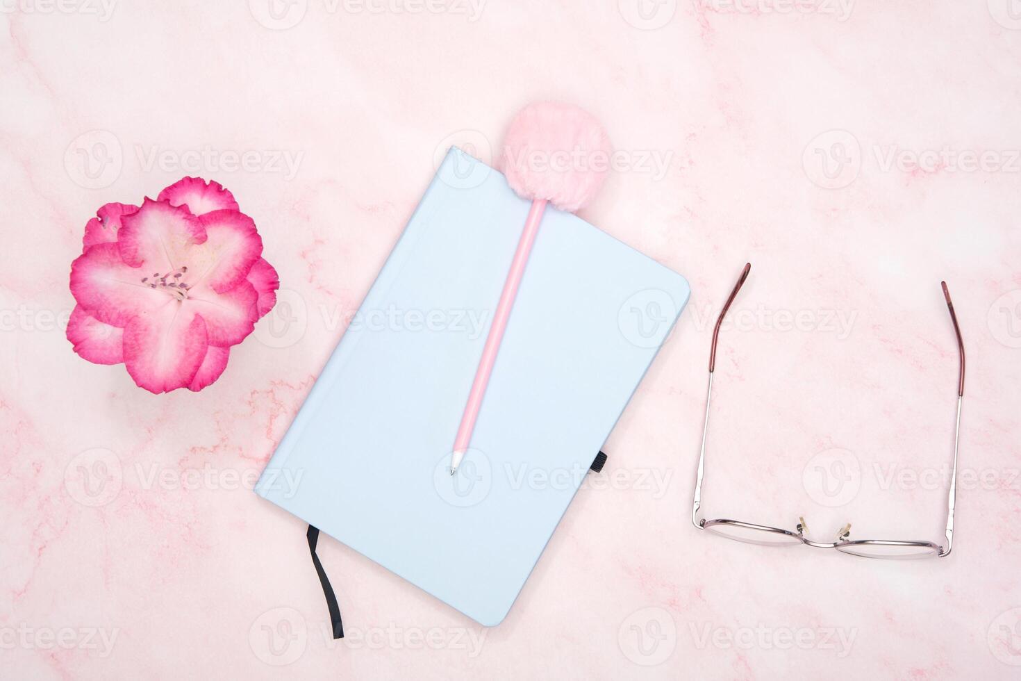 blue notepad with a pen on a pink table, workplace of a female student photo