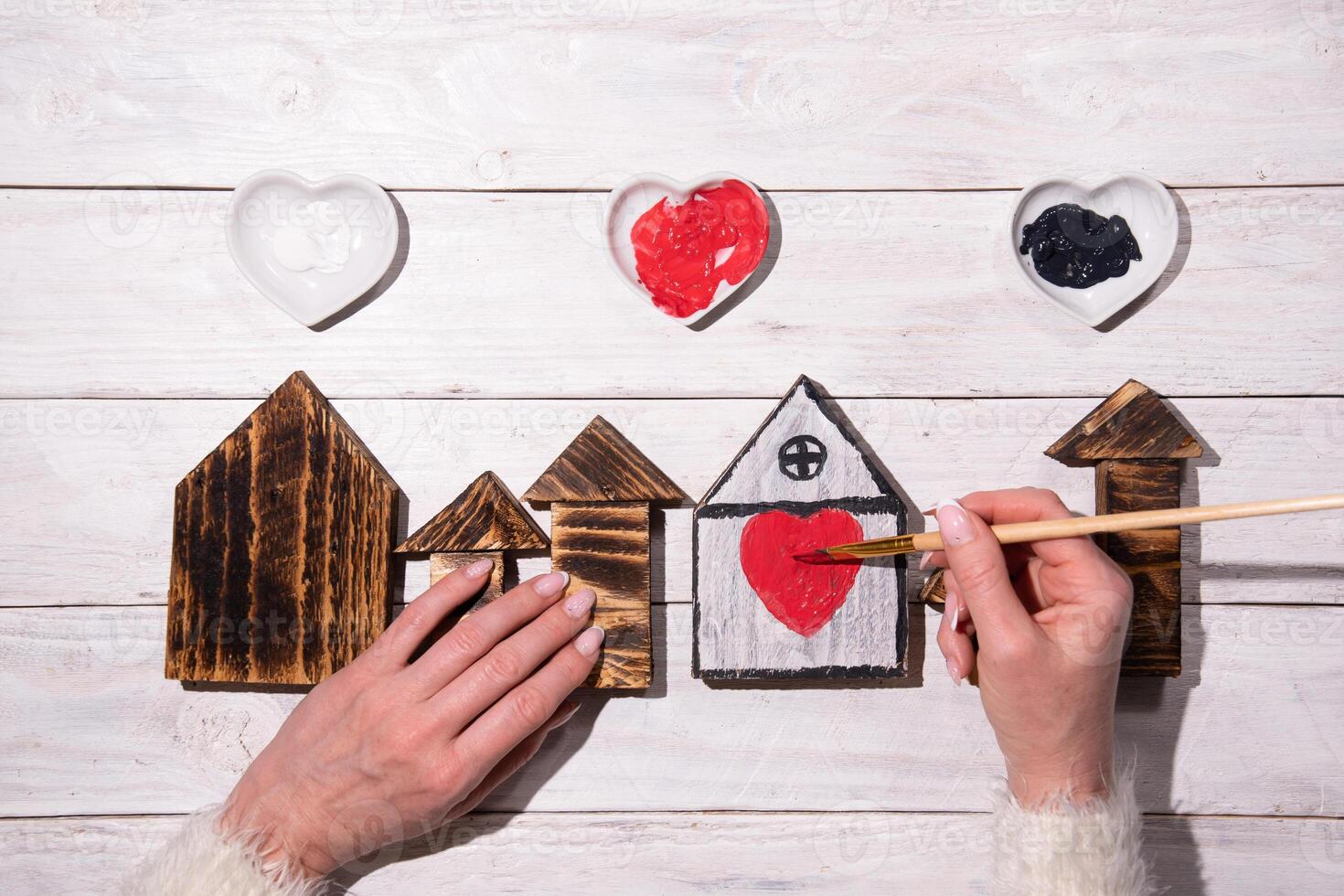 female hands draw a heart on a wooden house,step by step diy,crafting Sweet Home photo