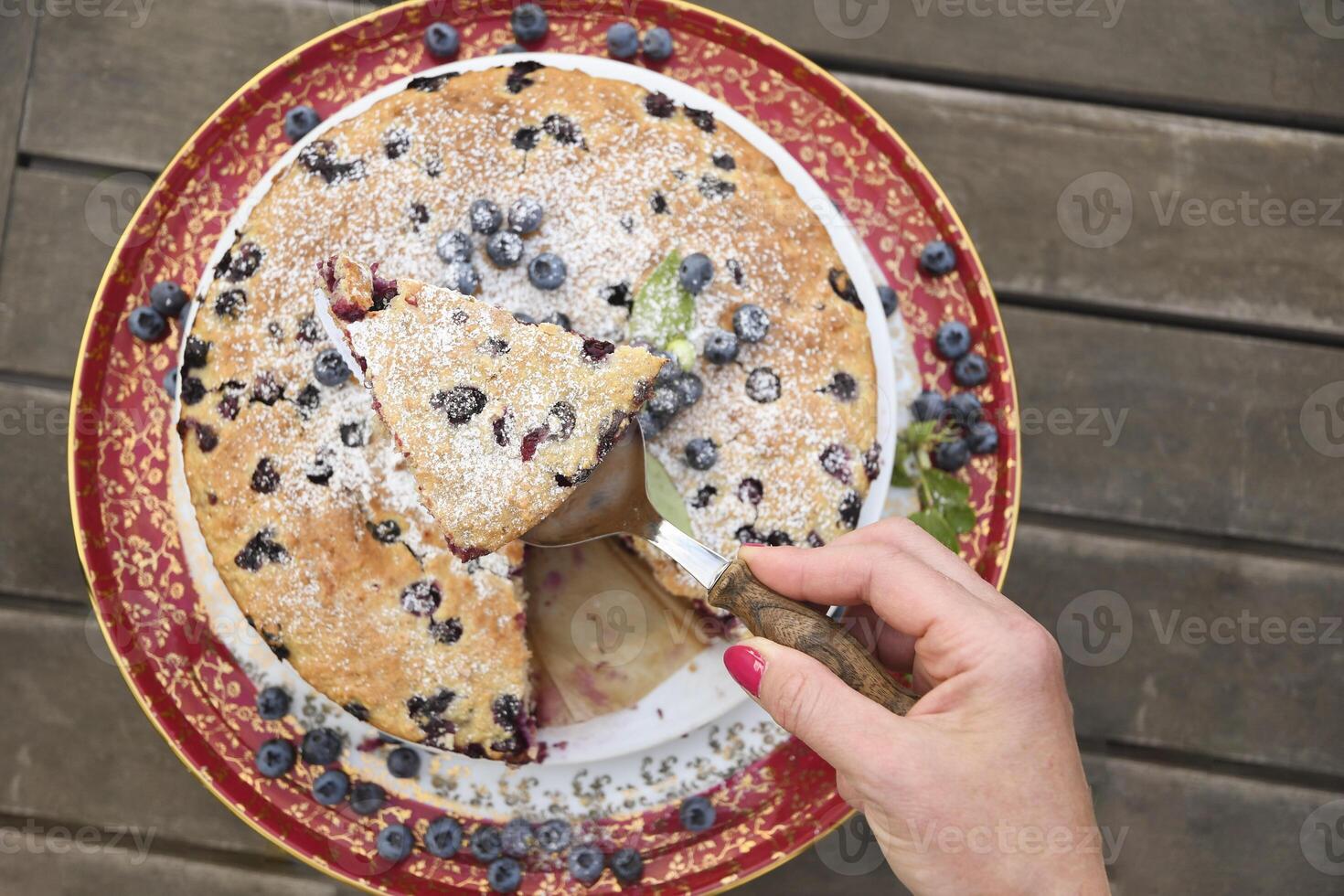 a woman's hand holds a piece of blueberry pie, a summer sweet dessert photo