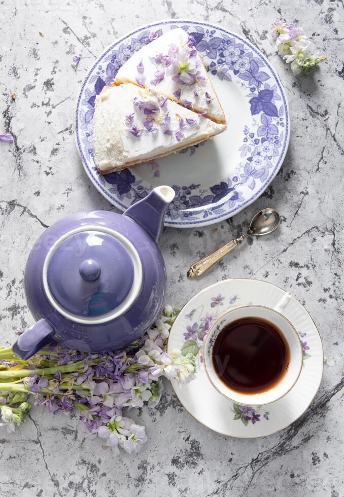 todavía vida con negro té y queso pastel, primavera ramo, delicado lila flores foto