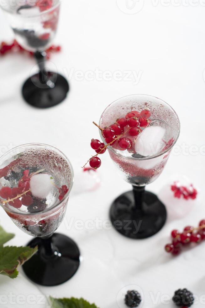 transparent gin and tonic with ice and fresh red currants and blackberries photo