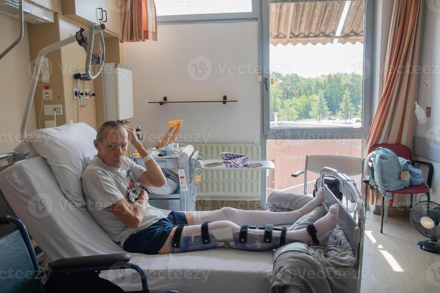 a man with a broken leg in an orthosis on a bed in a clinic after an accident and a fracture of the femur photo