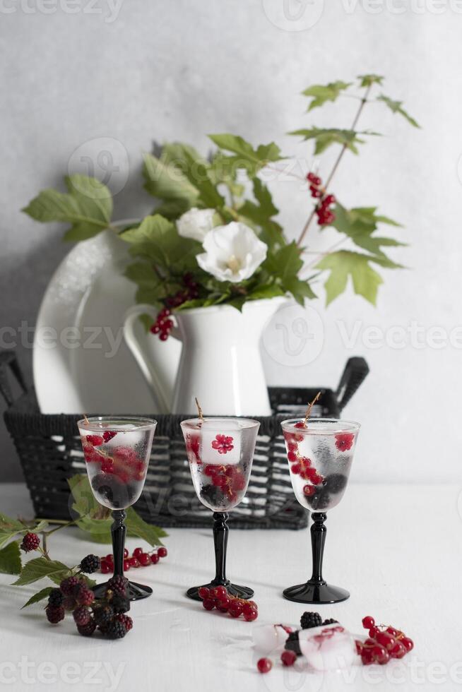 transparent gin and tonic with ice and fresh red currants and blackberries photo