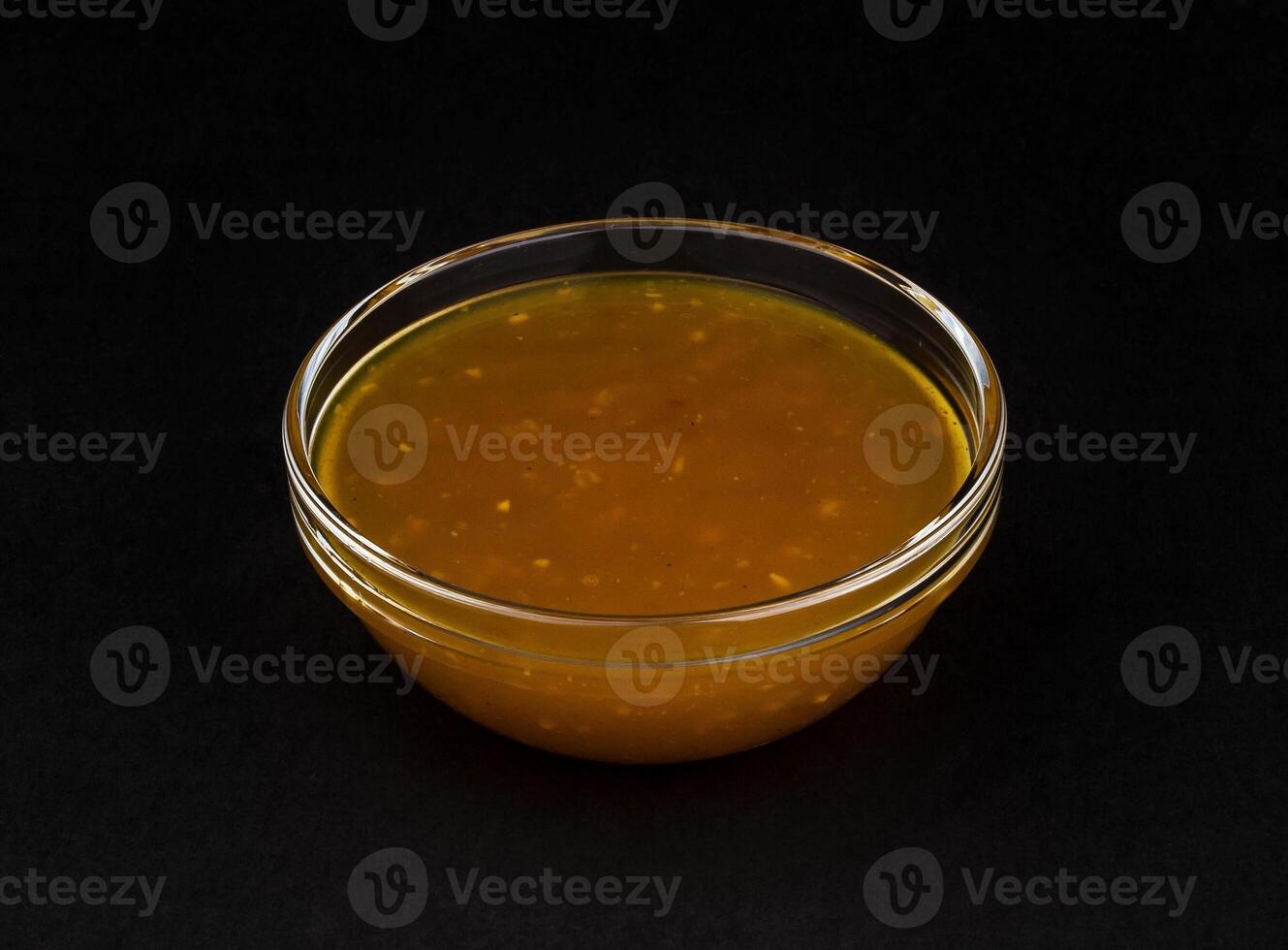 Sweet and sour sauce isolated on black background photo