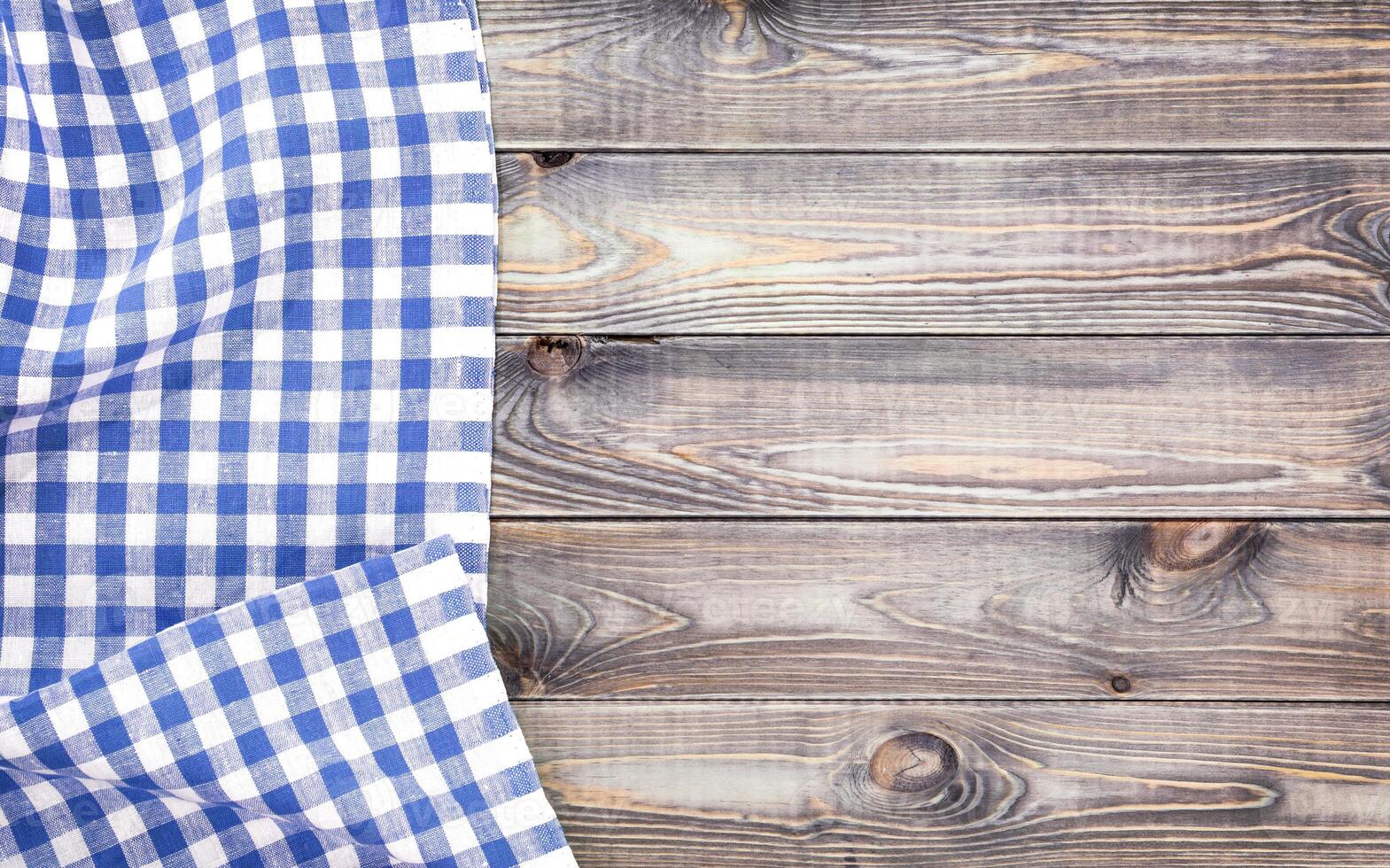 White old wooden table with blue checkered tablecloth, top view with copy space photo