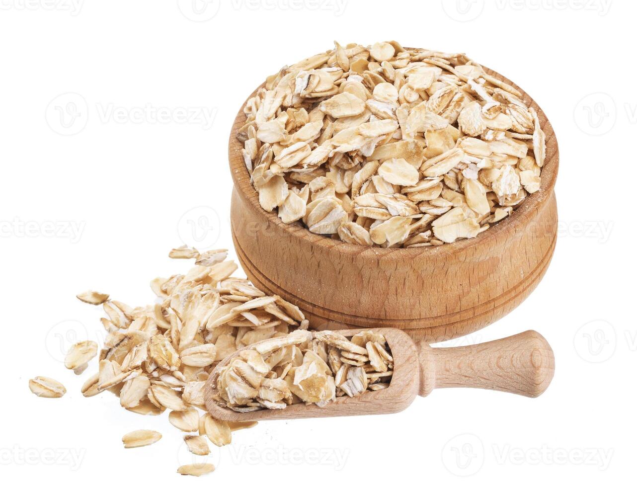 Isolated oat flakes. Wooden bowl and scoop with oatmeal on white background. Close-up photo