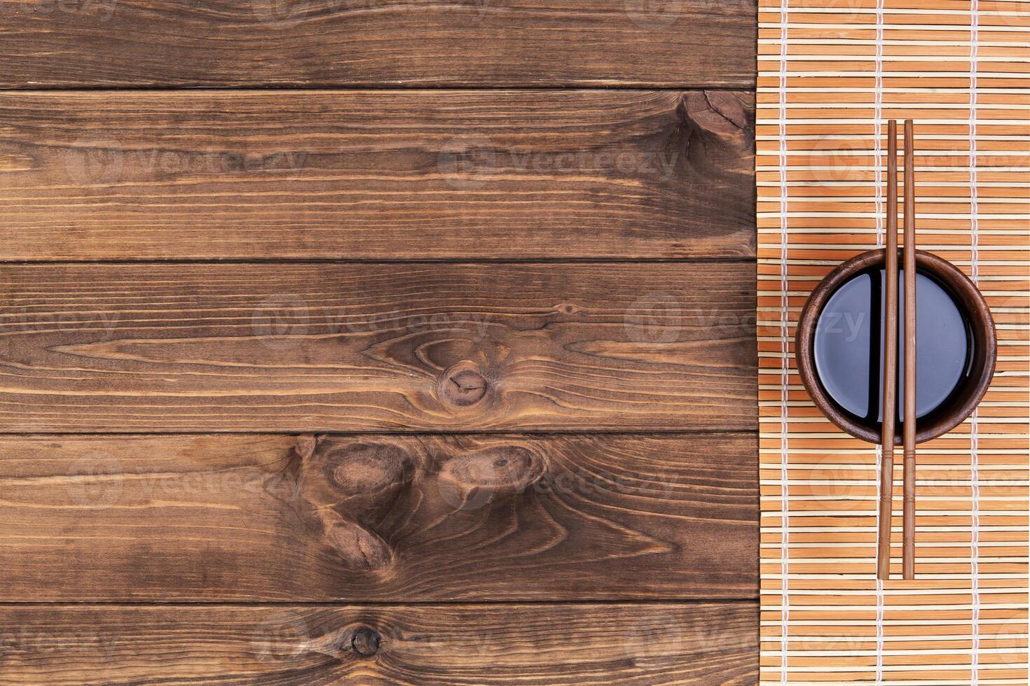 Mat for sushi and chopsticks on dark wooden background. Top view with copy space photo