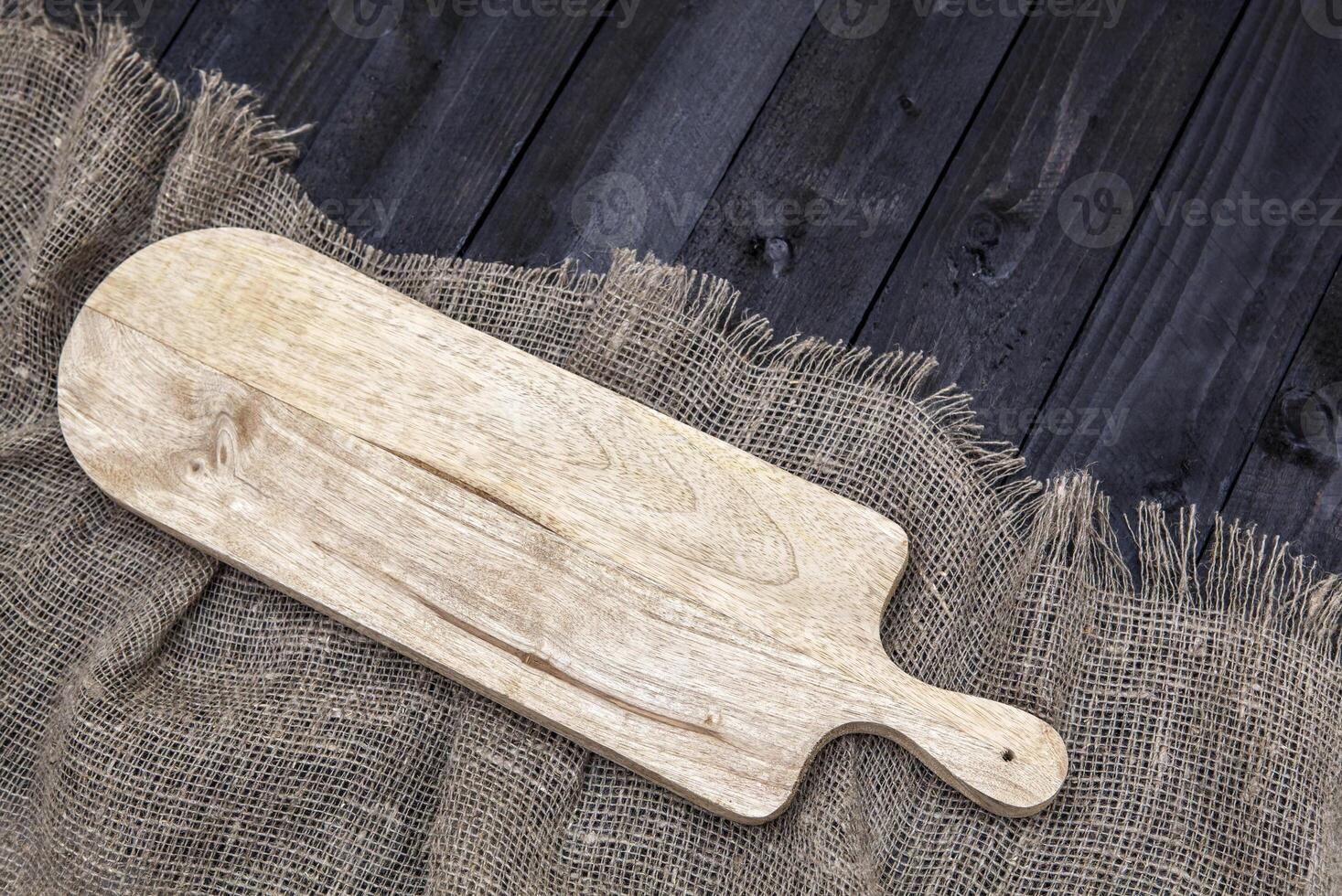 Black wooden table with burlap tablecloth and cutting board, top view photo