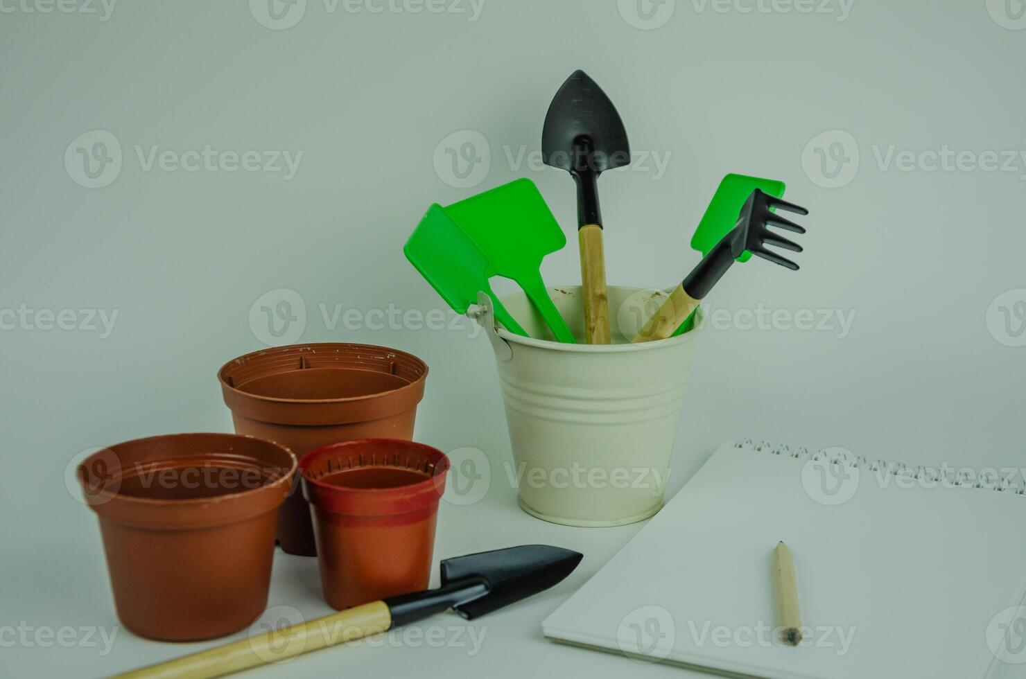 garden objects on a light background, watering can pots for planting, shovels with rakes for working in the garden and vegetable garden. High quality photo