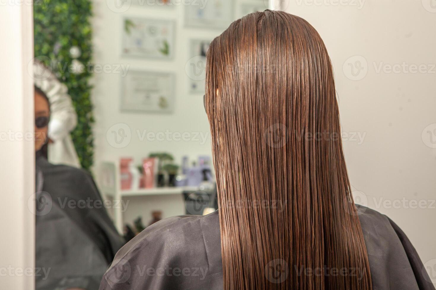 photo of a European girl with long and beautiful brunette hair at the beauty salon. Shiny and healthy hair.