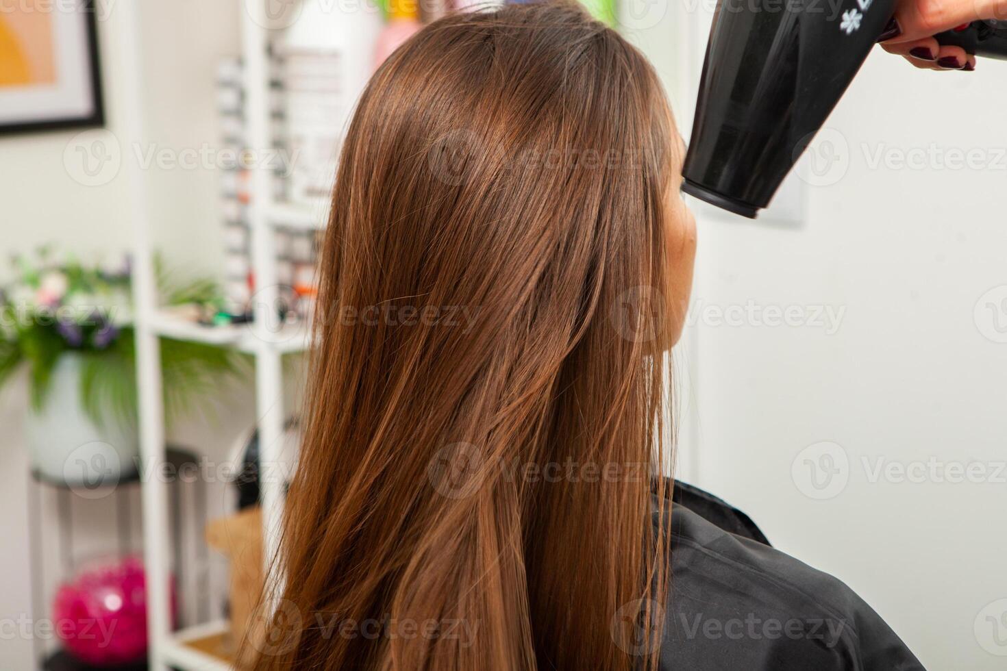photo of a European girl with long and beautiful brunette hair at the beauty salon. Shiny and healthy hair.