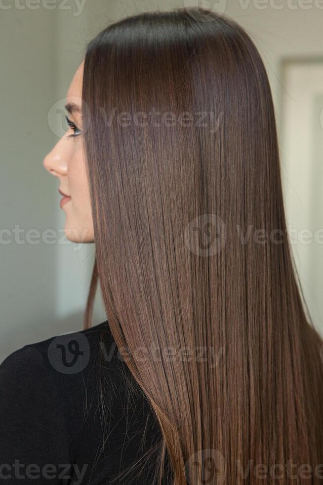 photo of a European girl with long and beautiful brunette hair at the beauty salon. Shiny and healthy hair.