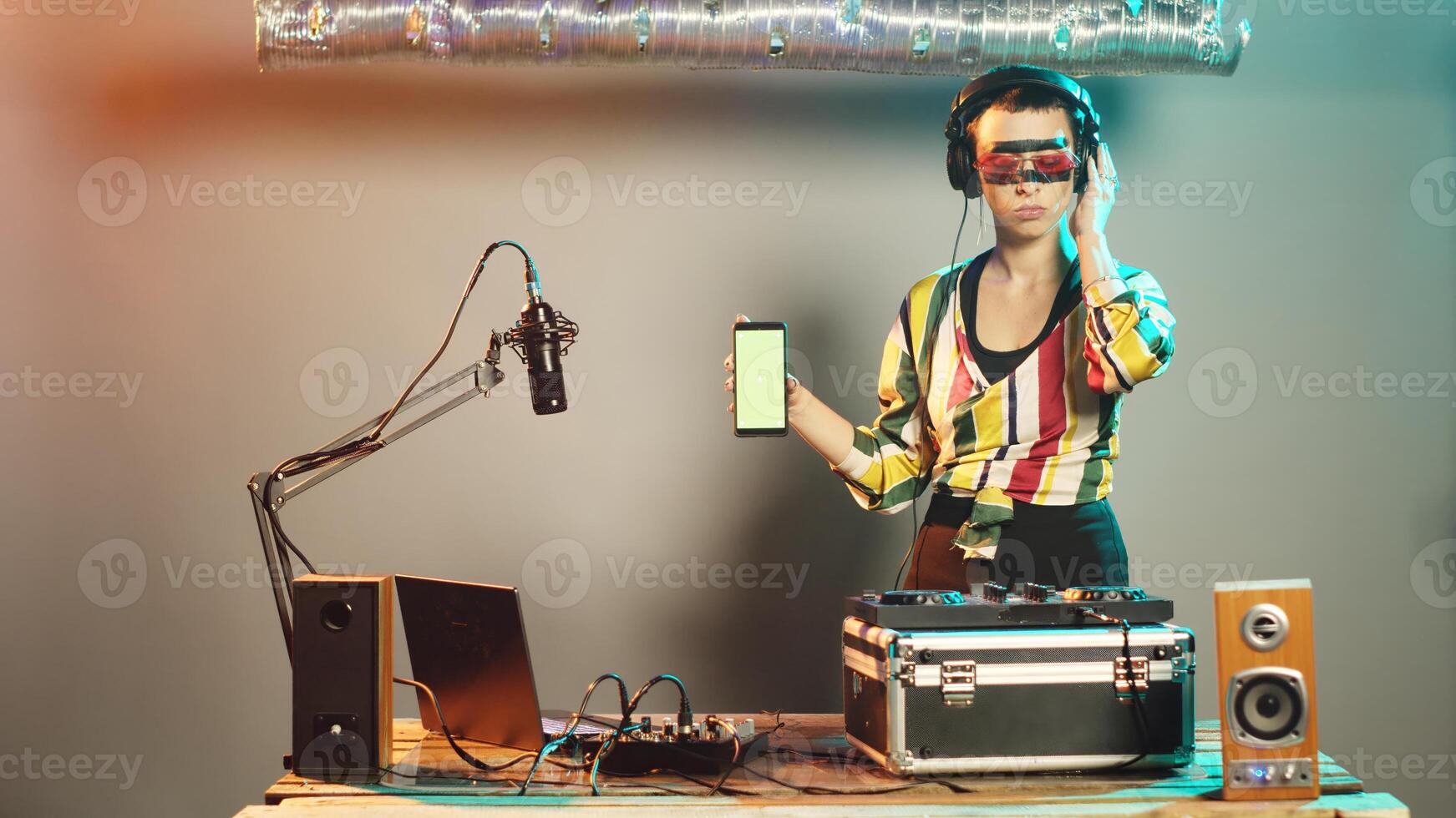 DJ artist shows greenscreen template while she uses turntables control keys for bass adjustment, creating modern techno music at nightclub party. Woman musician with chromakey template. photo