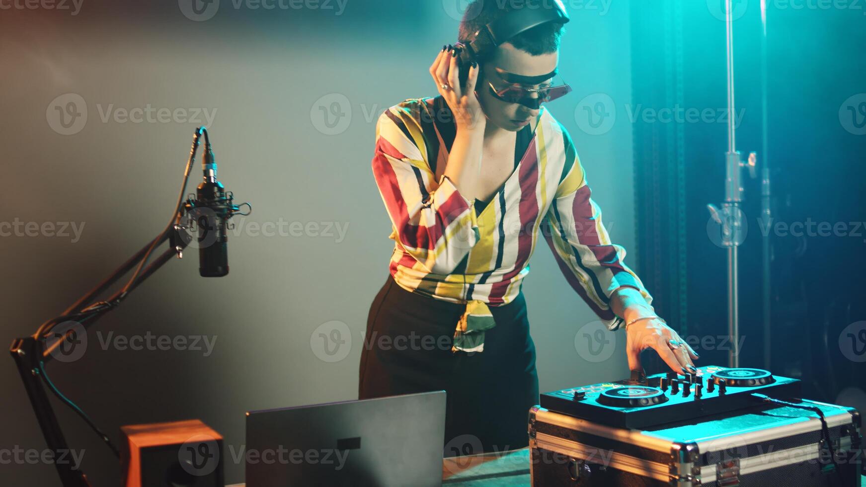 Techno mixer playing key sounds on turntables, using audio and stereo dj equipment to mix electronic music. Performer enjoying remixed records at nightclub stage party. Handheld shot. photo