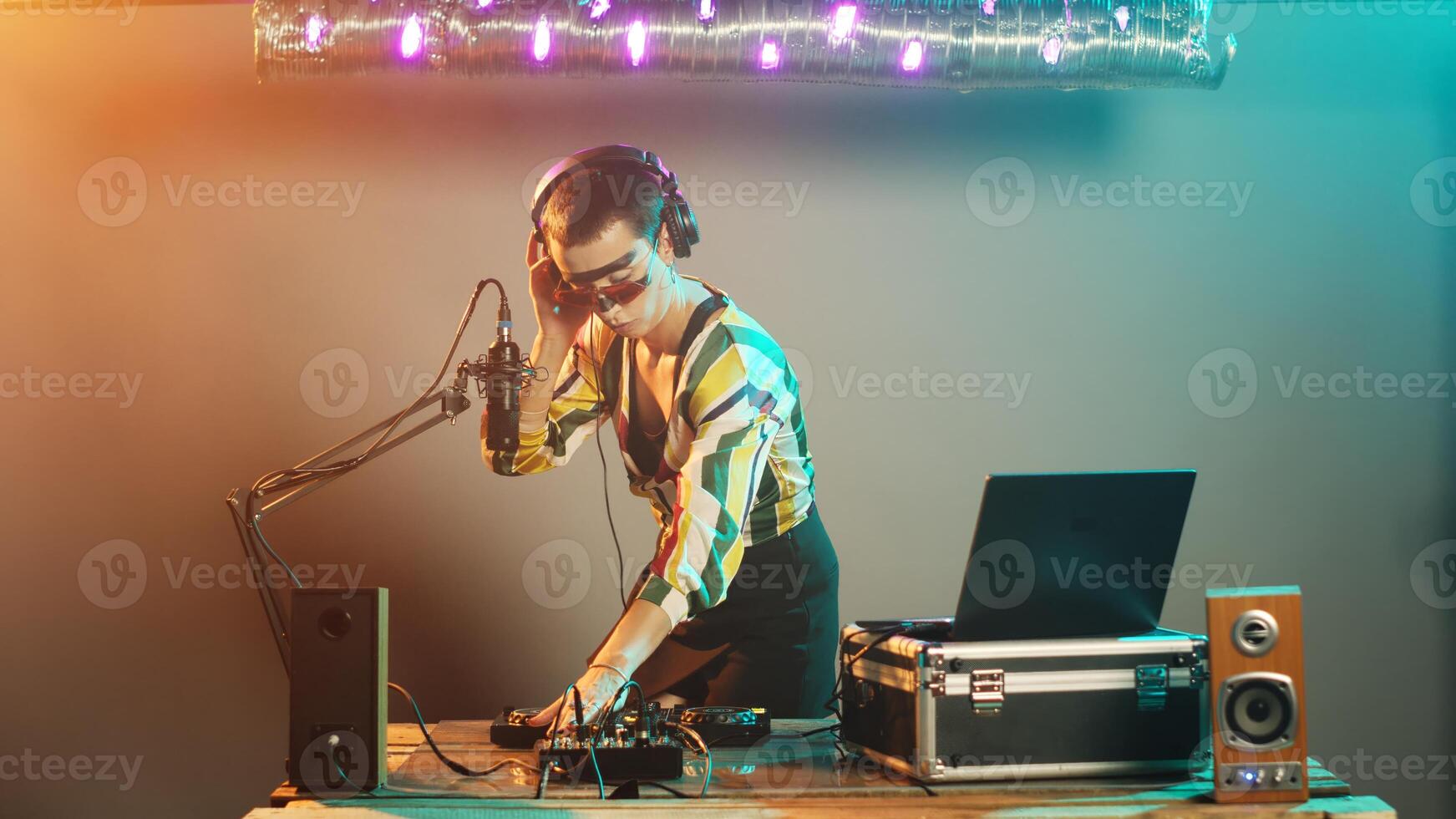 Focused woman playing tunes at dj turntables, creating techno performance with remix music at mixer with bass control key. Mixing records with audio electronic instruments. Tripod shot. photo