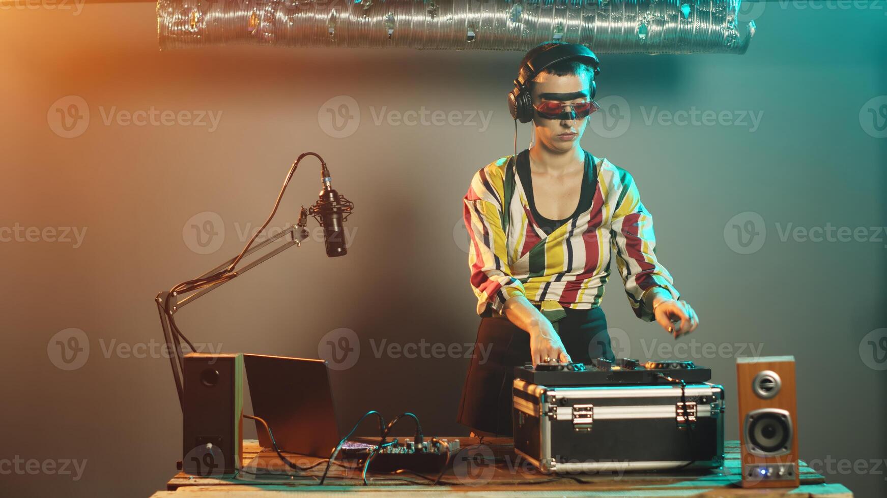 Talented disc jockey using vinyl to mix music at turntables, creating remix of modern records at electronic instrument. Mixing with audio control panel on nightclub stage. Tripod shot. photo