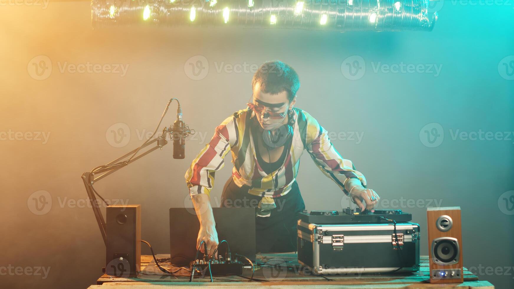 Woman artist mixing techno sounds with turntables equipment, modern musician playing disco tunes and remix at stereo electronic mixer. Performing with control keys and buttons. Tripod shot. photo