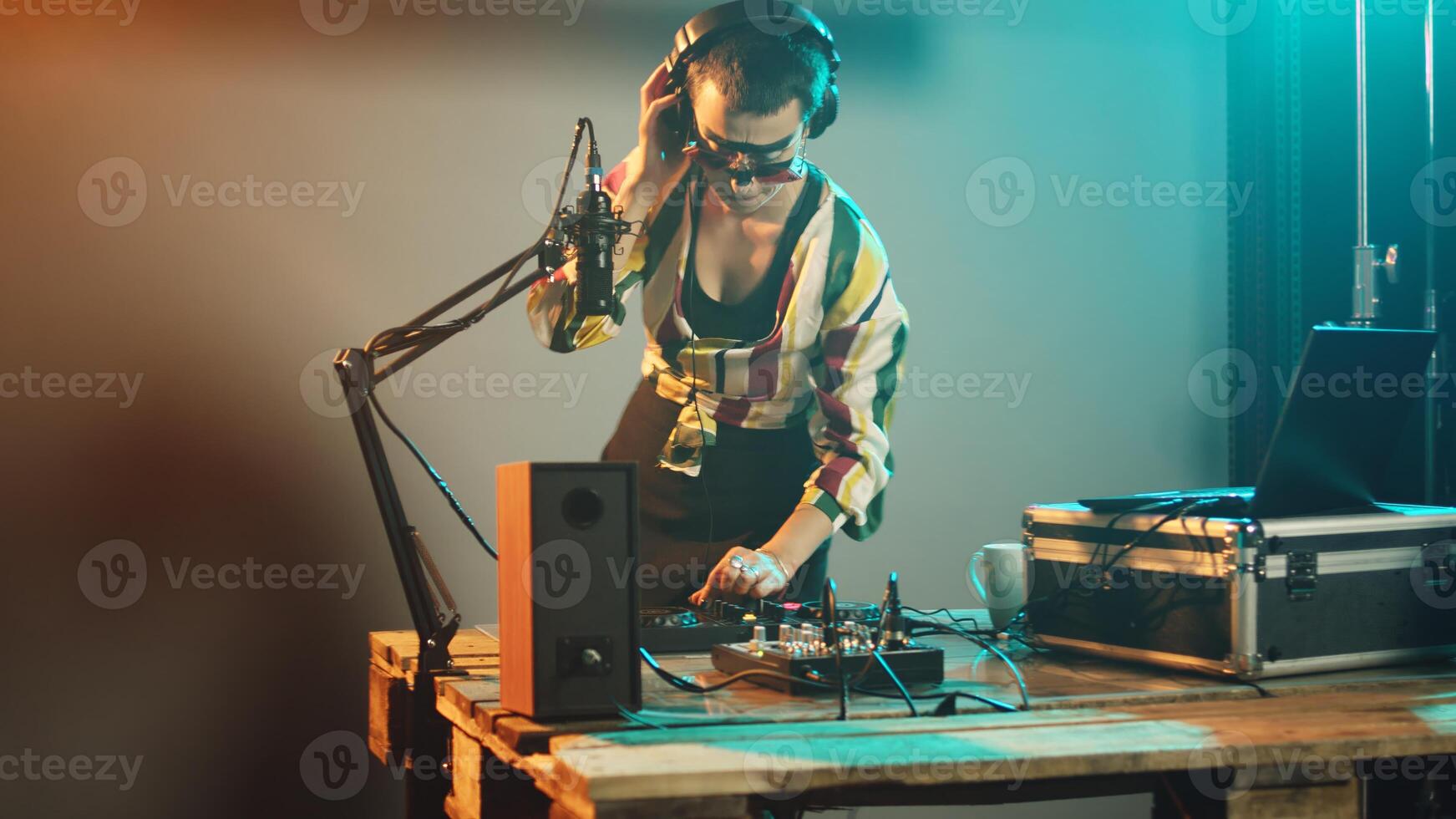 Female performer using mixing turntables and buttons to play remixed songs at party, having fun with audio dj board for techno nightclub. Playing bass sounds with electronics. Handheld shot. photo