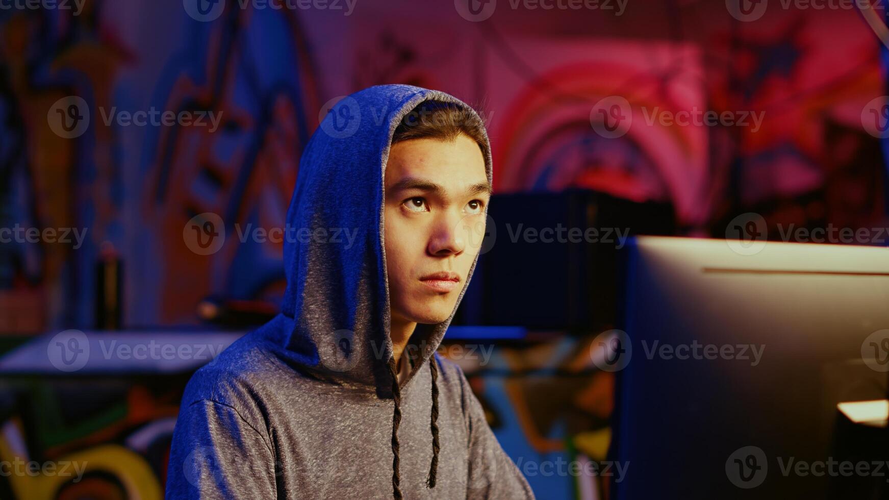 Close up shot of asian hacker hiding in underground bunker, being mindful of his surroundings, feeling nervous after stealing data from victims using virus, precautious about being caught by police photo