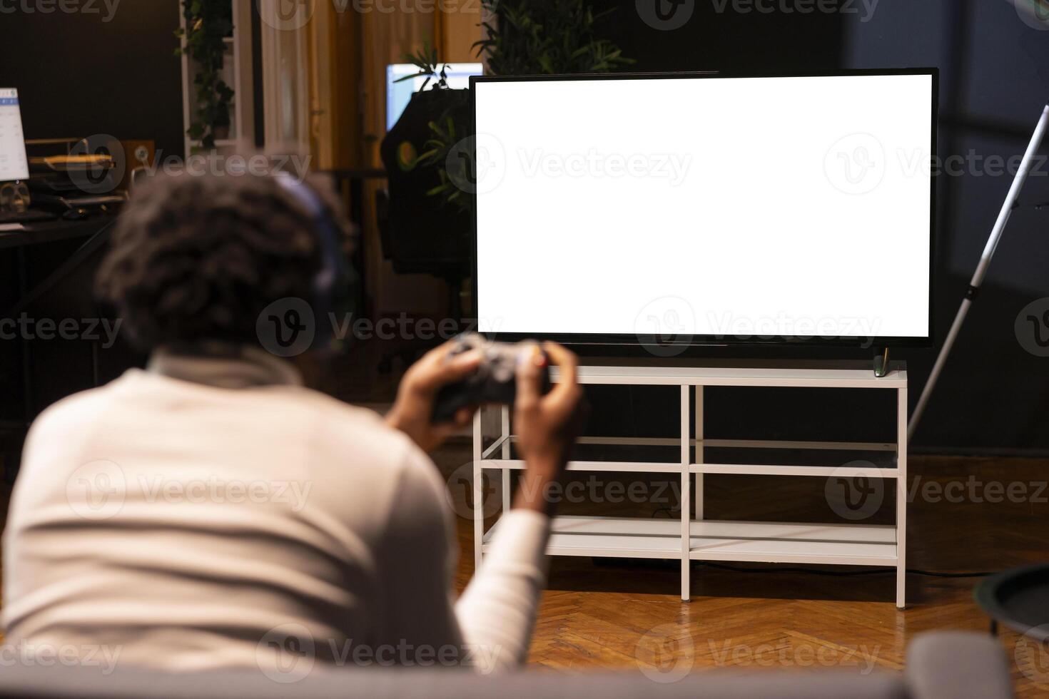 Man playing videogames on isolated screen TV, relaxing after long day at work. Competitive gamer having fun on mockup display gaming console in stylish apartment living room photo