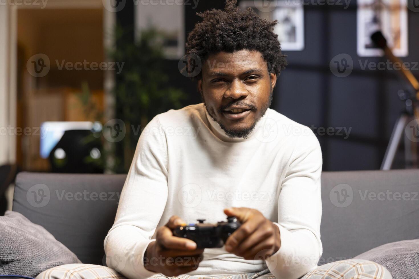Happy man playing shooter videogame in warm apartment, holding controller. Gamer participating in online multiplayer game using gaming system, spamming buttons on gamepad photo
