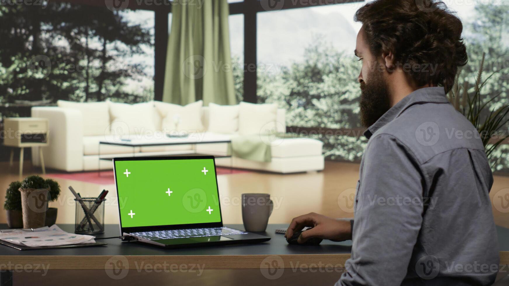 Billionaire stakeholder unwinds in front of greenscreen display on his laptop, exquisite mountain lodge. In a successful business functioning, foreign manager operates with blank mockup screen on pc. photo