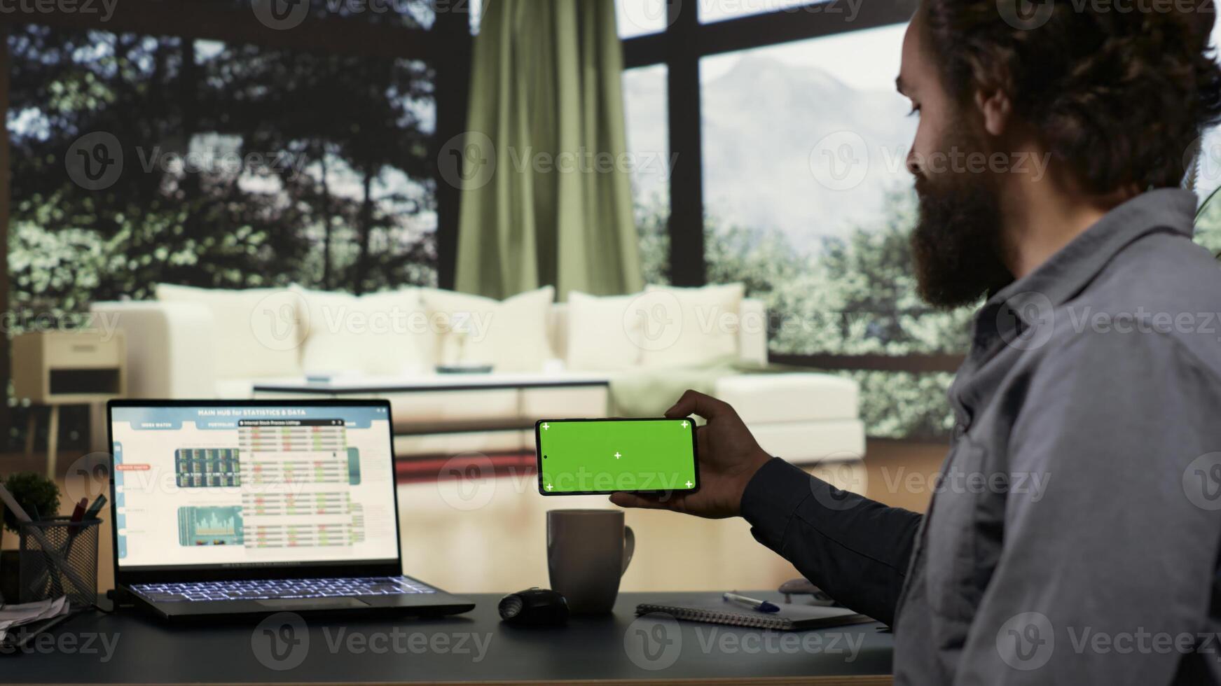 Wealthy businessman checks greenscreen on mobile phone layout, working to increase international profit from his opulent modern mansion in the woods. Entrepreneur uses blank copyspace display. photo