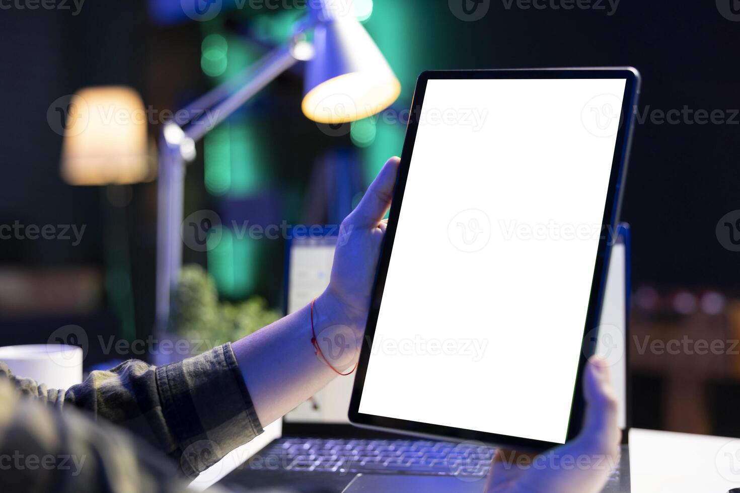 Closeup of an individual vertically holding digital device with blank white screen display. A person grasping electronic tablet showing isolated chromakey mockup template. photo