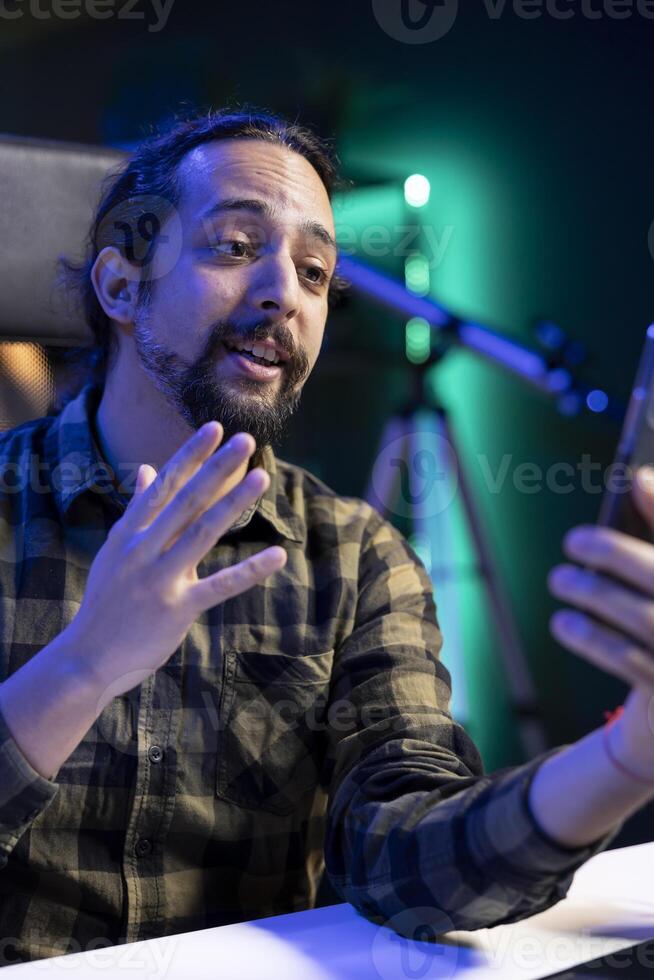 Detailed view of male university student having a video call conversation on his mobile device. Young man discussing with colleagues in a virtual meeting on his smartphone. photo