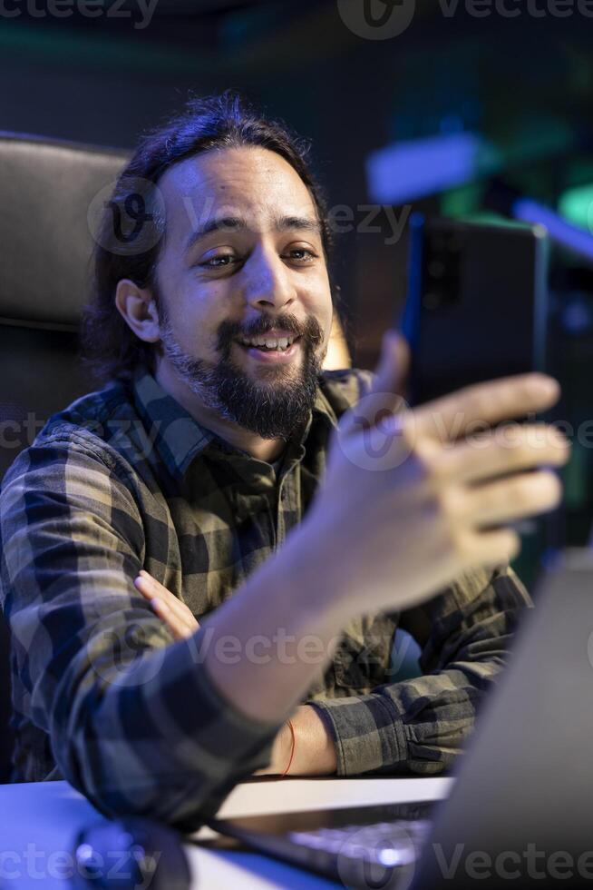 Closeup of happy male individual taking a selfie using his smartphone. Smiling bearded man grasping his mobile device and making a video for his social media accounts. photo