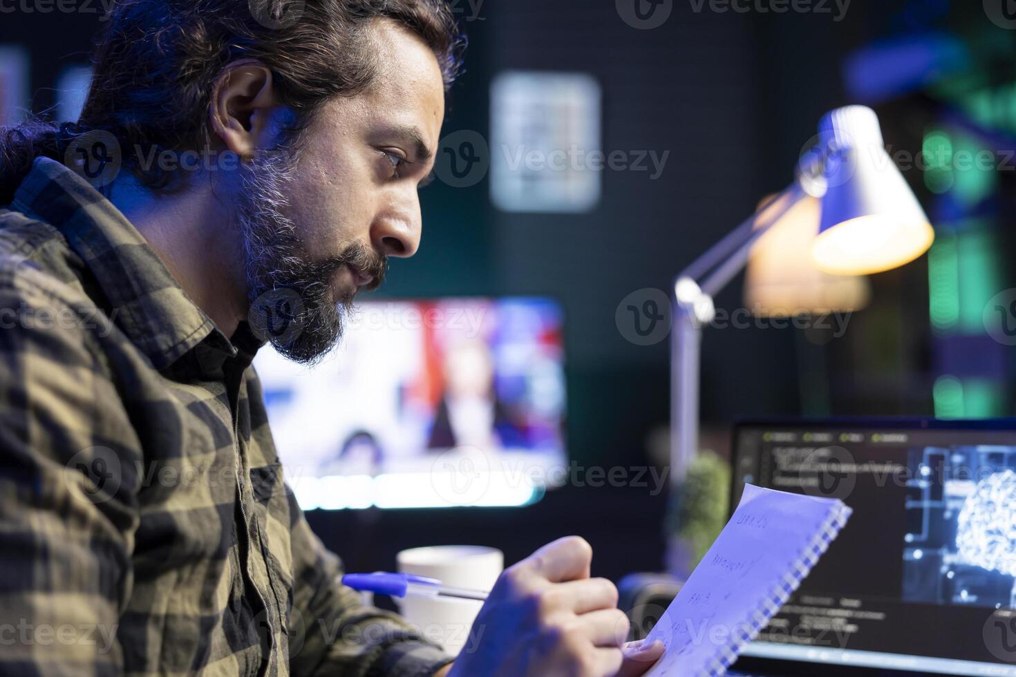 Closeup of man working on laptop, using AI to develop a futuristic software and taking down notes. Male individual writing new code in his notebook, showing his skill in programming and cyber security photo