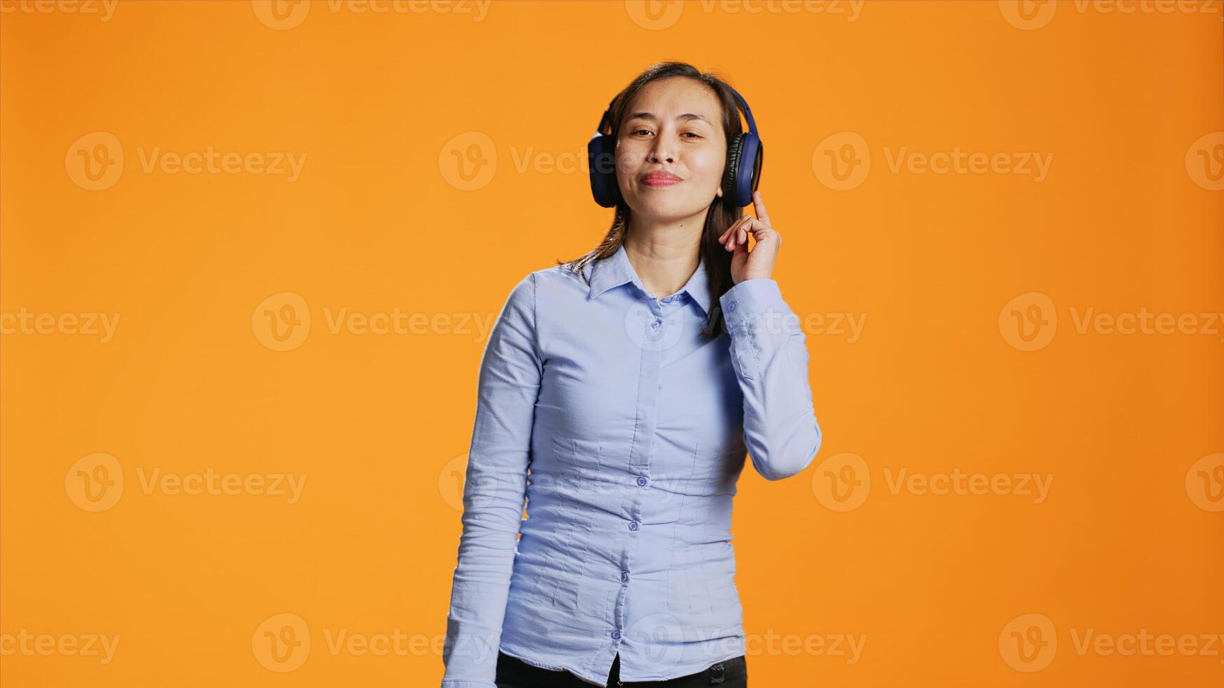 Happy person listens to music on headphones and dancing on camera, having fun with radio songs on audio headset. Young joyful woman showing groovy dance moves and enjoying tunes. photo