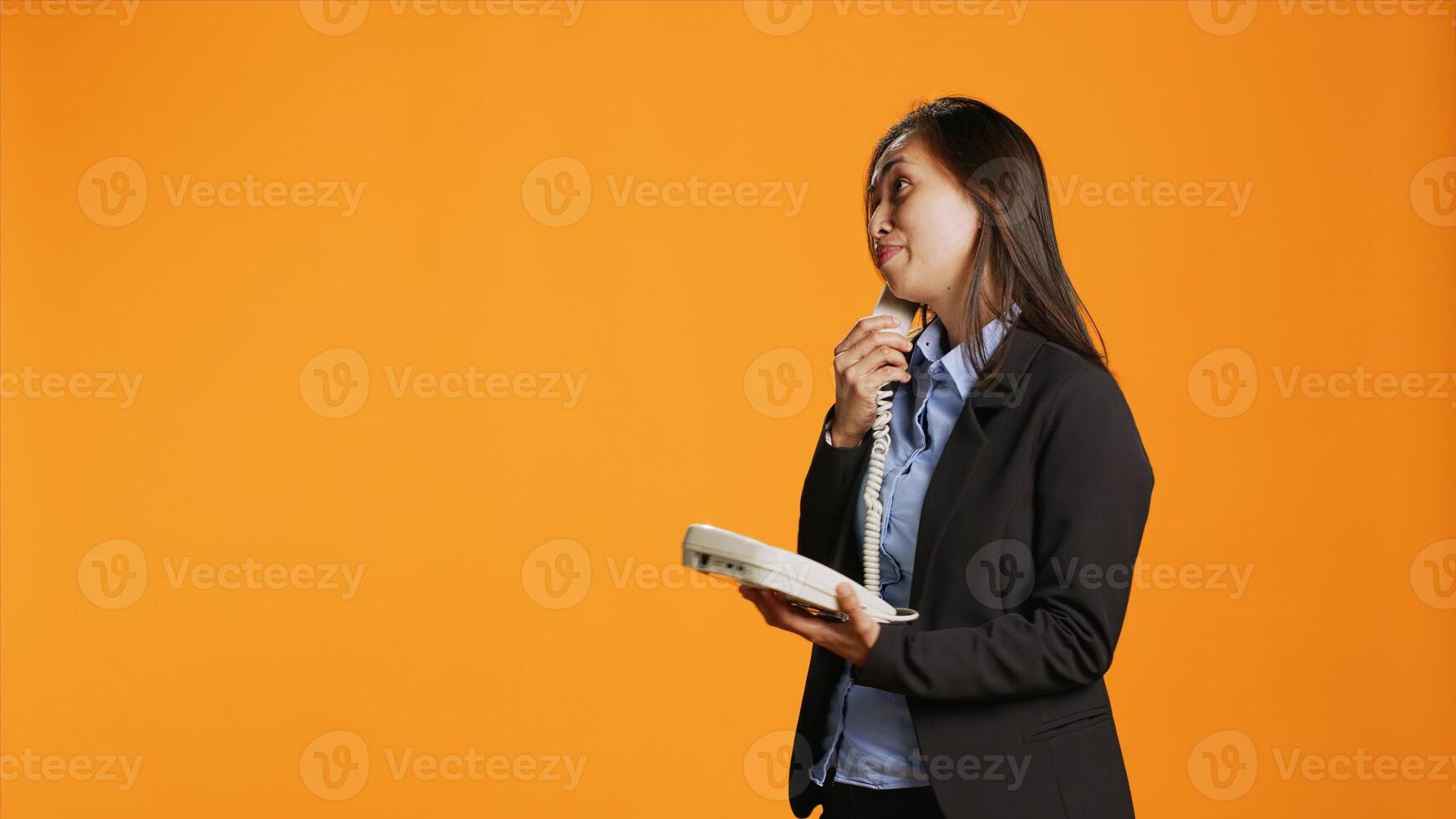 Business manager answers landline phone call to discuss about important matters, using vintage telecommunication line. Asian woman in formal suit chatting on retro telephone with cable. photo