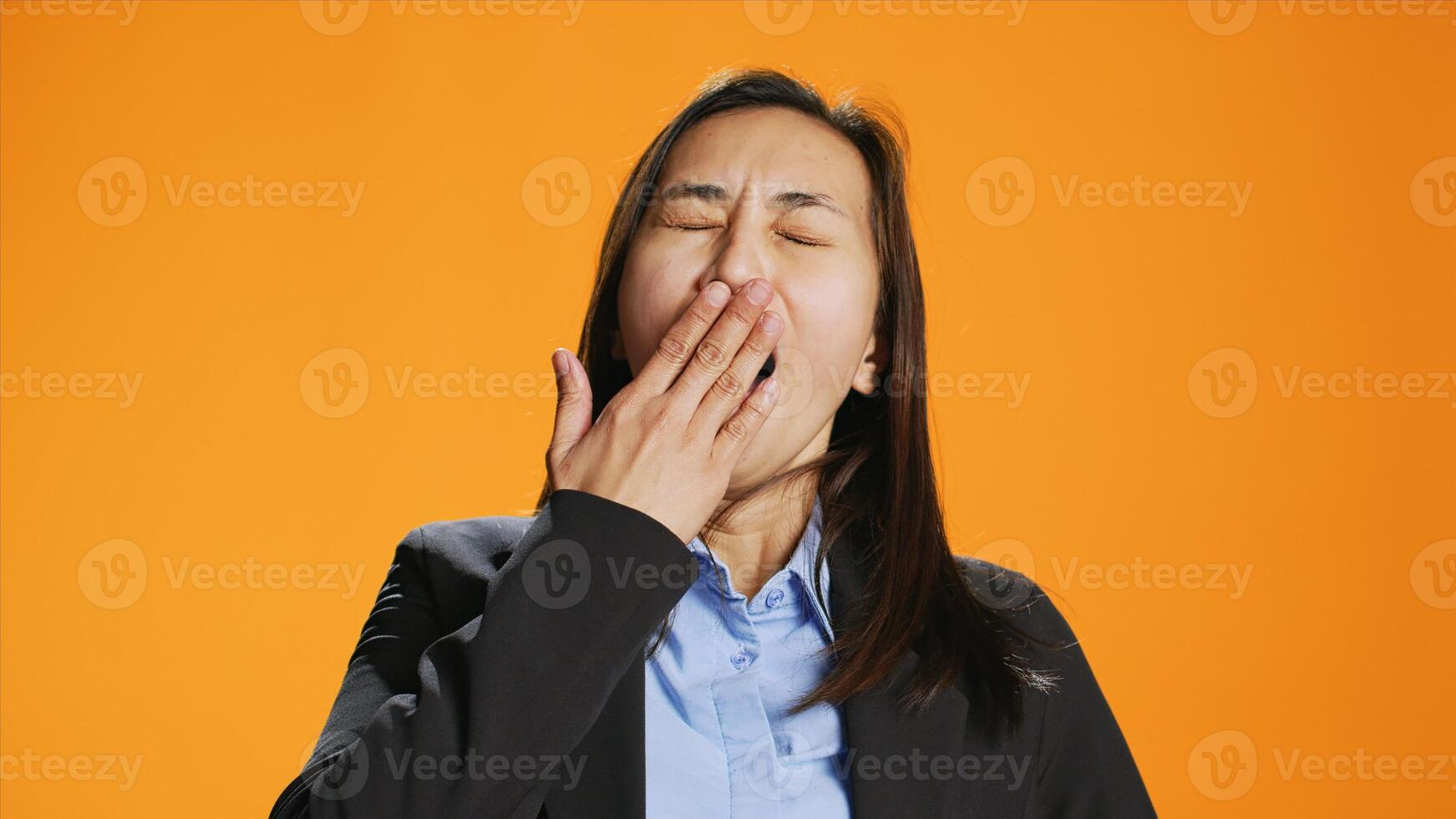 Exhausted person in formal clothes yawning and feeling sleepy in studio, trying to be awake and not fall asleep on camera. Young asian woman being tired and stressed, expressing burnout. photo