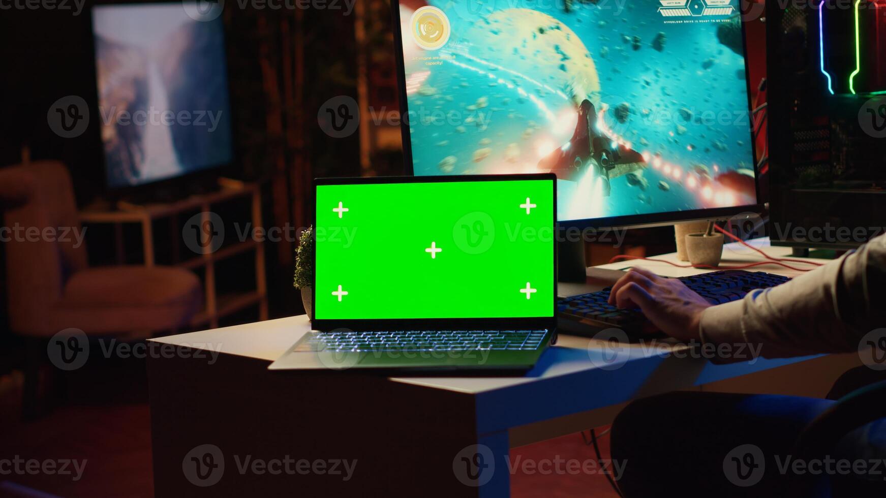 Mockup laptop next to man playing high FPS singleplayer videogame with spaceship shooting laser streams at asteroid. Green screen notebook near gamer using crosshair overlay to hit targets in SF game photo