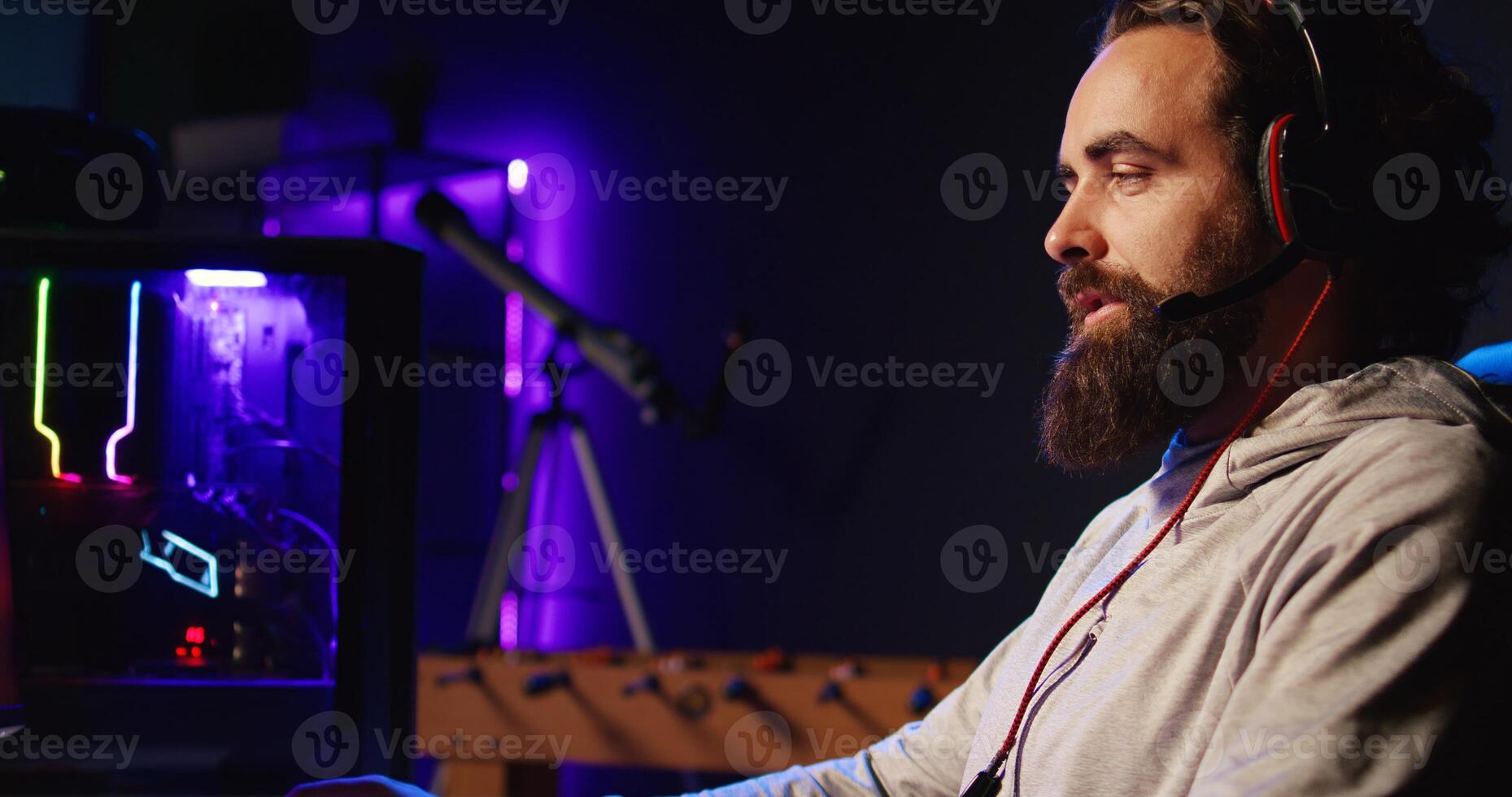 Man relaxing by playing science fiction FPS videogame with friends on PC in RGB lit apartment late at night. Happy gamer talking with teammates, shooting enemies in online multiplayer shooter photo