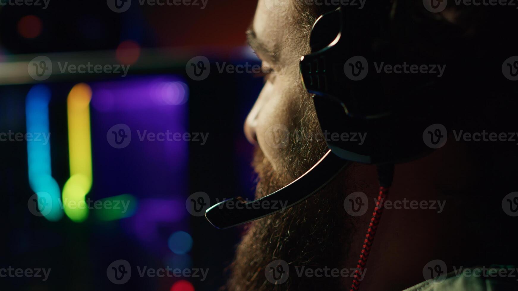 Man talks with teammates online while playing video games on gaming PC, extreme close up. Gamer battling enemies in multiplayer shooter, discussing with other players through headphones mic photo