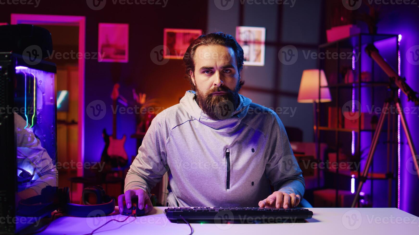 Focused man playing videogames at home, spamming keyboard buttons trying to defeat enemies. Competitive pro gamer trying hard to win online multiplayer esports tournament, zoom out shot photo