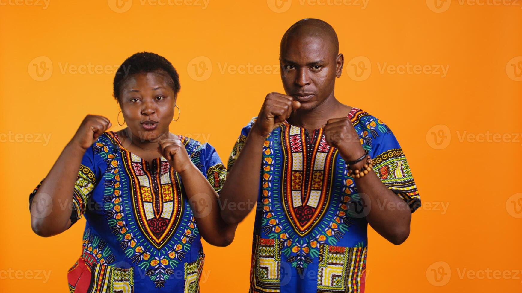 Strong mad couple throwing punches ready for fight, posing in studio with clenched fists. Aggressive man and woman preparing to do boxing activity, fighters in dangerous position on camera. photo