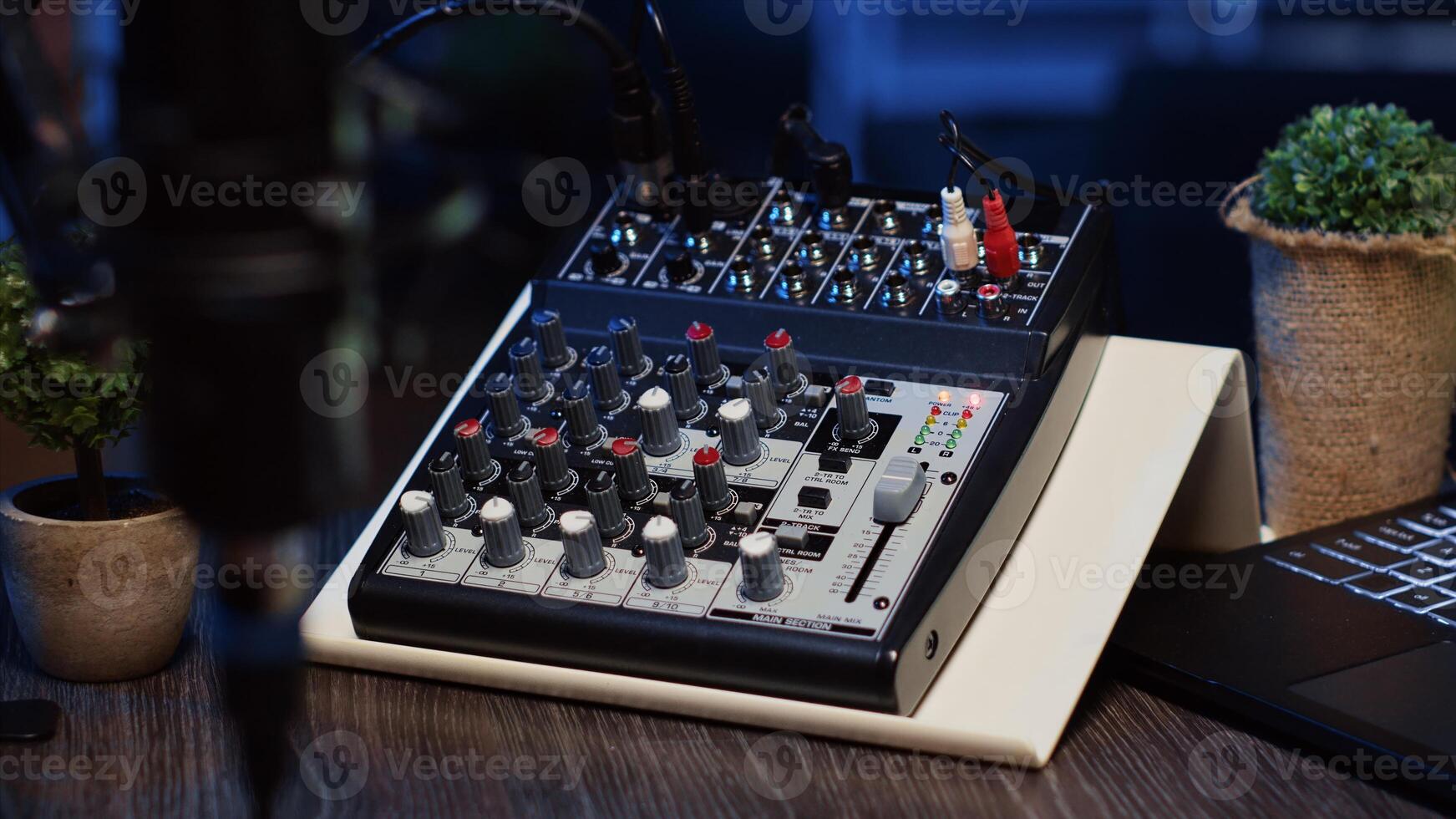 Panning shot of professional analog mixer and microphone used to produce high fidelity audio during podcast recording session in studio. High tech recording devices on table in apartment photo