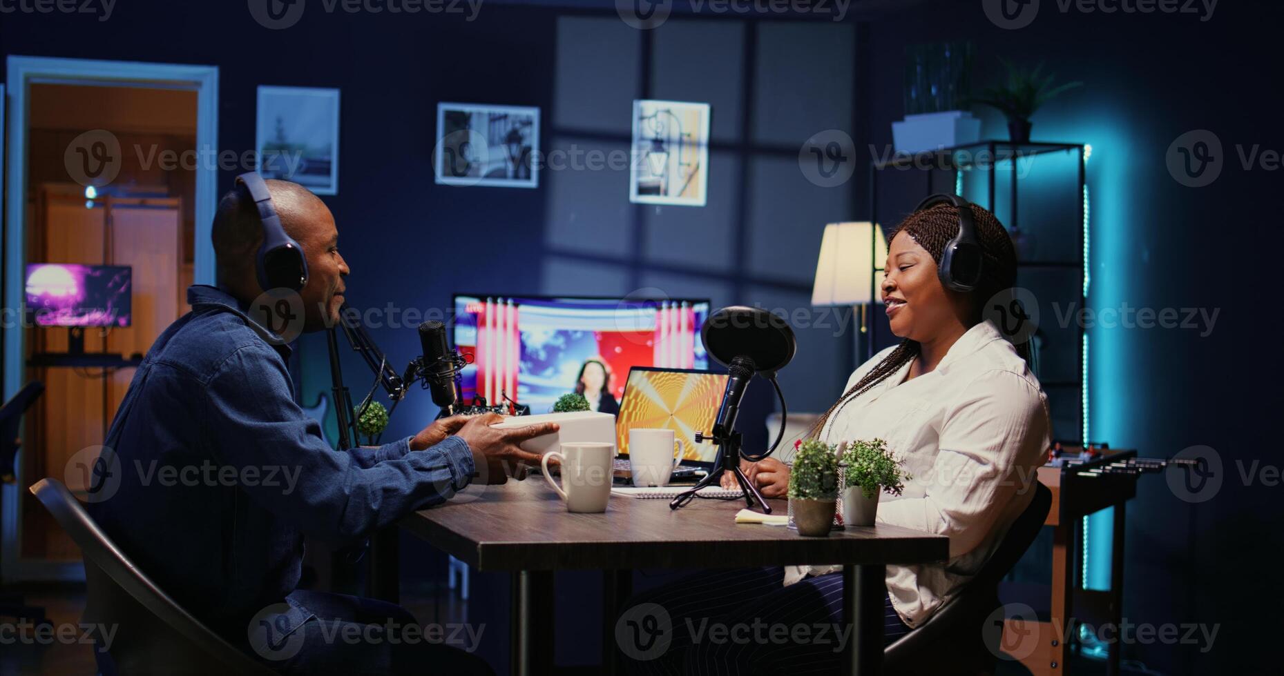 Tech journalist recording podcast with guest in studio, unboxing newly launched smartphone. Podcasters producing technology related content for internet show, unpackaging and reviewing mobile phone photo