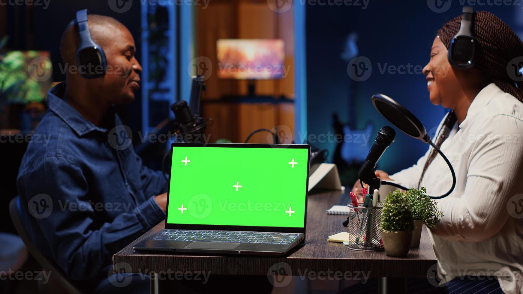 Green screen laptop next to man on podcast discussing with guest during marathon stream for humanitarian cause. Mockup notebook near host chatting with celebrity, gathering donations from audience photo