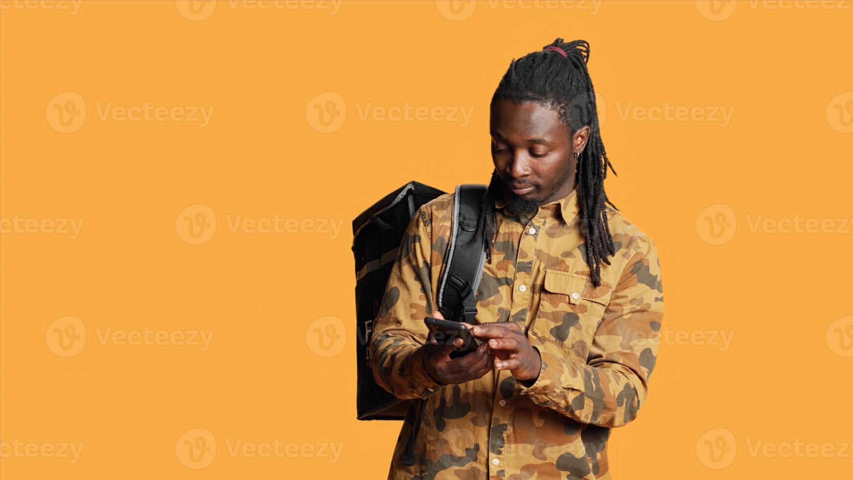 Male courier delivering fast food restaurant order with backpack, bringing takeaway meal for client at their home. Deliveryman working on takeout with thermal bag, looking for the address. photo