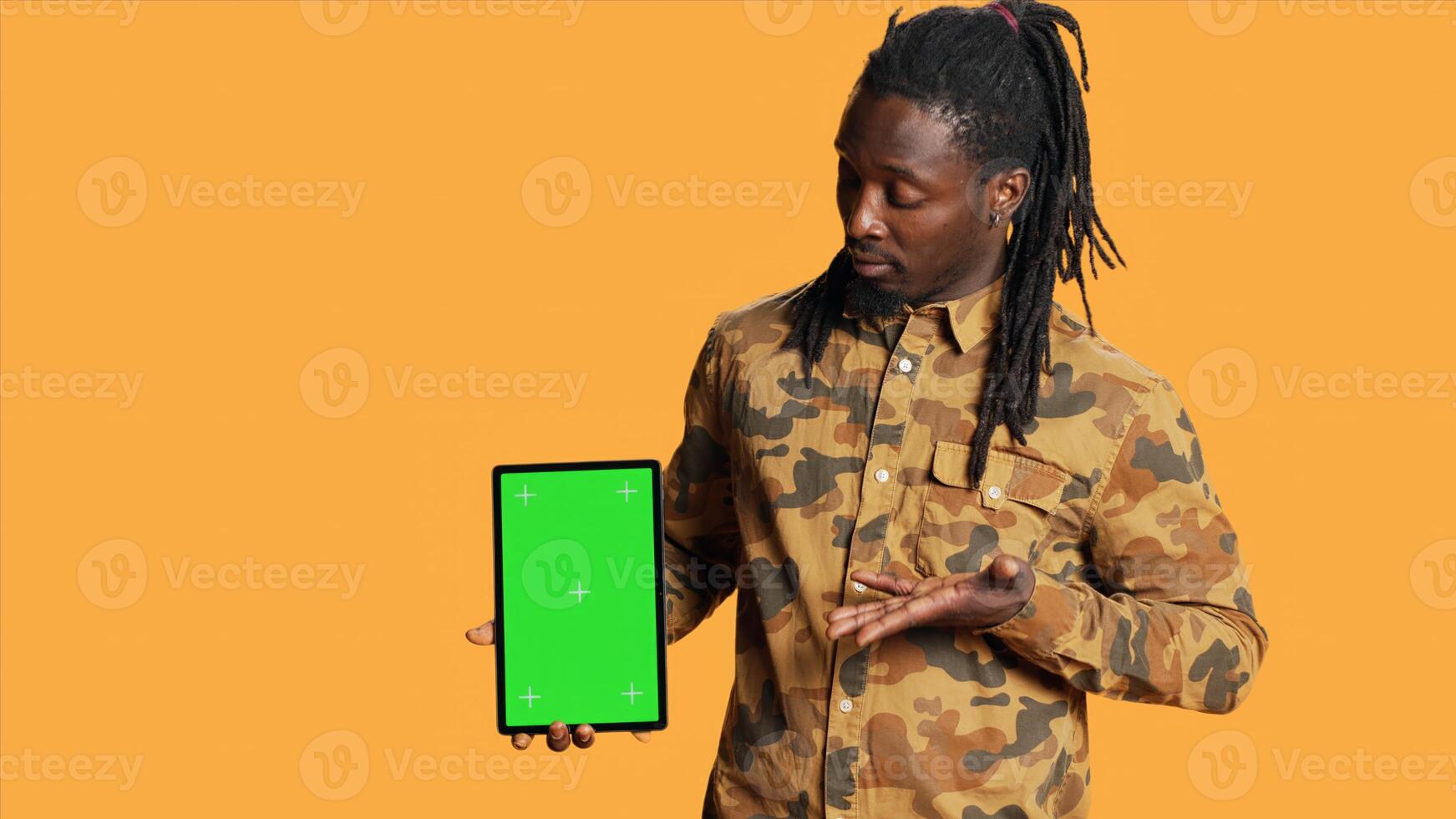 African american guy shows greenscreen on tablet, presenting isolated chromakey display and smiling in front of camera. Young adult holding mobile device with copyspace blank layout. photo